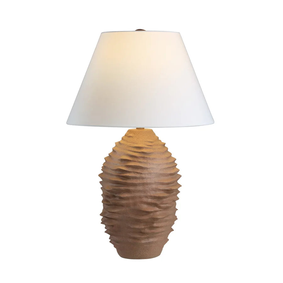 A table lamp with a textured, ribbed ceramic base in a warm brown tone and a white tapered fabric shade, shown lit against a plain white background.