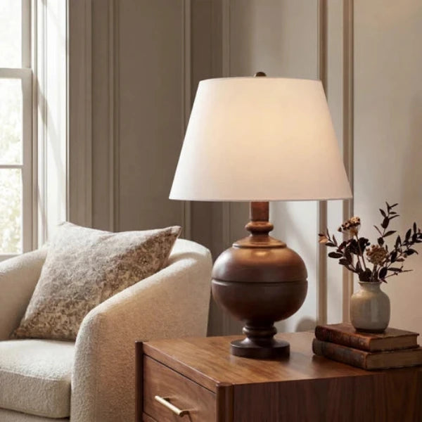 A classic table lamp with a dark brown wooden ball-shaped base and a tapered off-white fabric shade, shown against a plain white background.