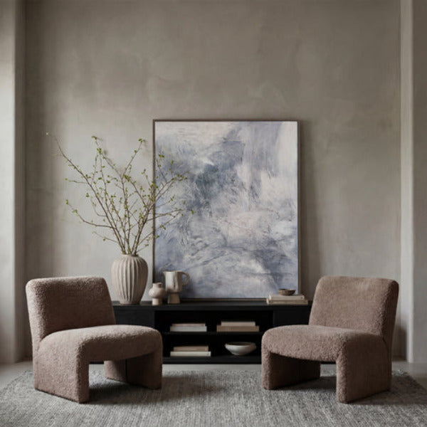 An abstract framed painting featuring textured brushstrokes in shades of gray, white, and muted blue-gray, enclosed in a dark brown frame against a solid white background.